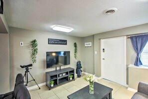 A living room with a TV, a golf bag, and a tripod.