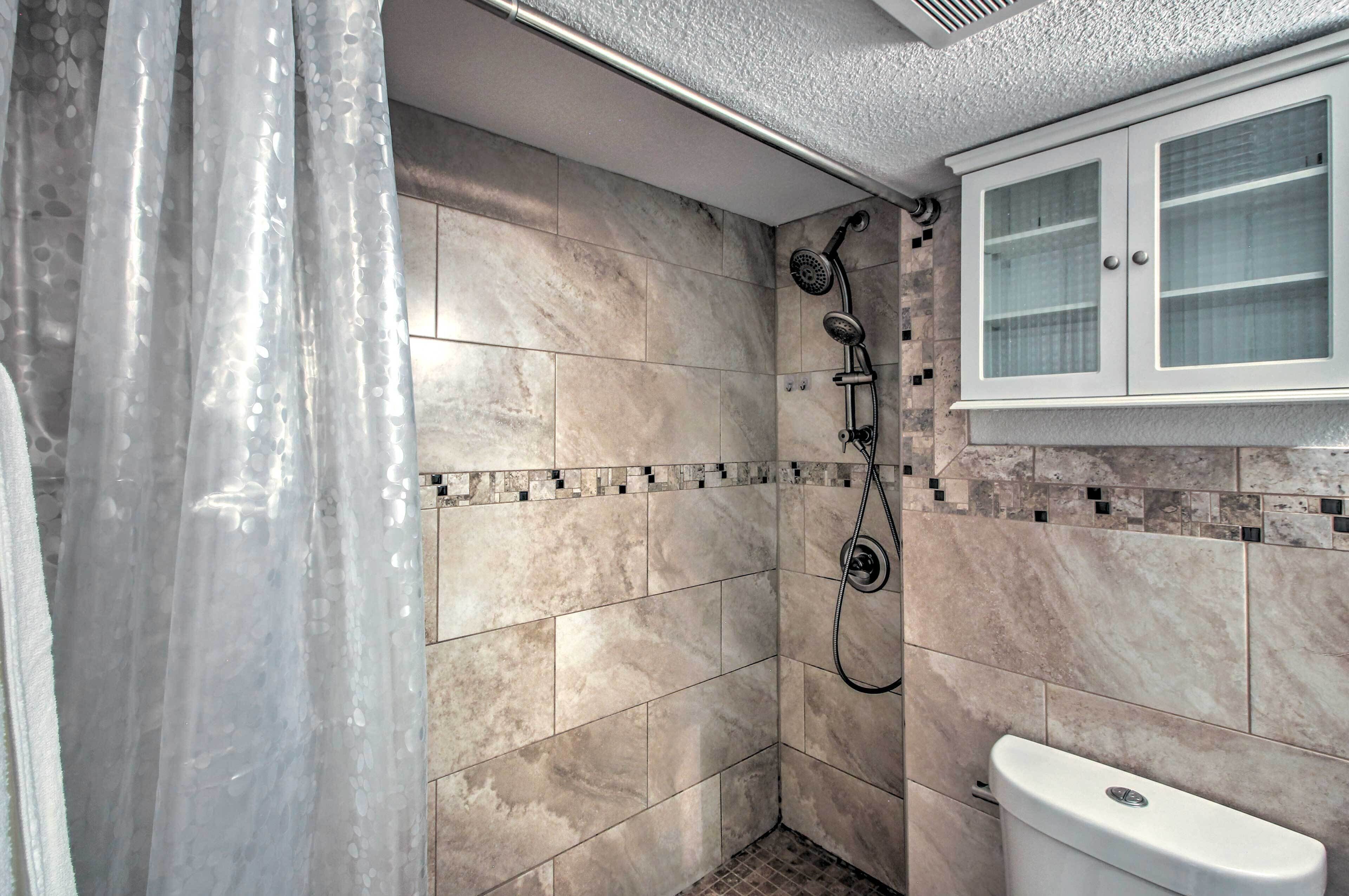Un baño con ducha, inodoro y un armario.