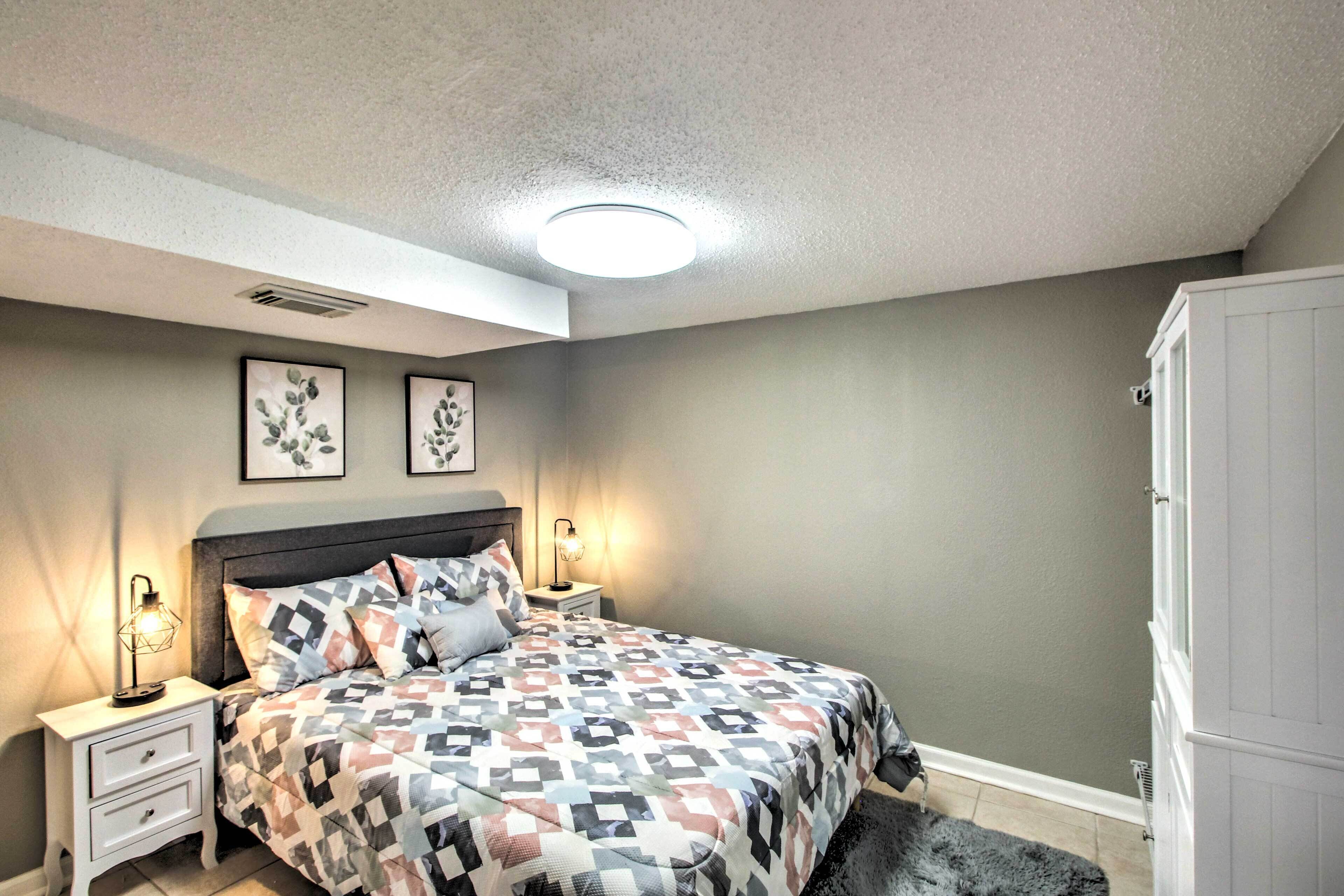 Un dormitorio con cama, mesitas de noche, armario y dos cuadros colgados en la pared.