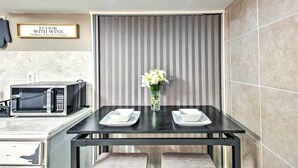 Une cuisine moderne équipée d’un four à micro-ondes, d’une table avec deux assiettes blanches et d’un vase rempli de fleurs.
