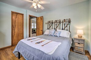 A bedroom with a bed, wooden headboard, bedside tables, and a ceiling fan. - Waterfront Lakeview Cottage w/ Dock & Lift! (Lakeview)