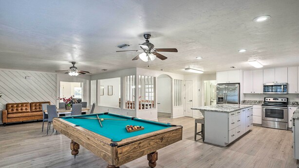 A modern living room with a pool table, a sofa, and a dining area. - Spacious Family Home w/ Backyard in Gainesville! (Gainesville)