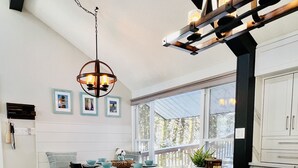 Uma cozinha moderna com uma ilha grande, banquetas, iluminação pendente e vista para o exterior.