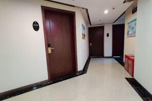 Un pasillo de hotel con una puerta de madera, un cartel con un número y un cartel en la pared.