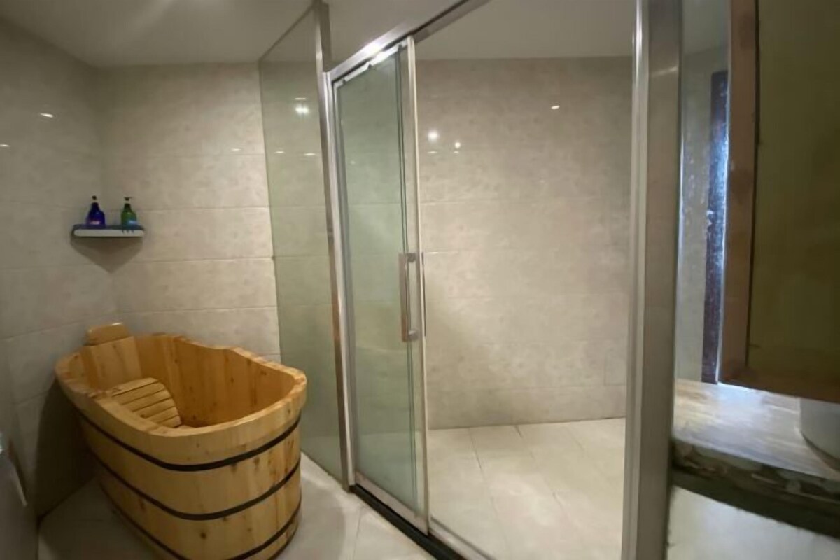 Ein modernes Badezimmer mit einer Duschkabine aus Glas, einer Holzwanne und einem Ablagebereich für Toilettenartikel.