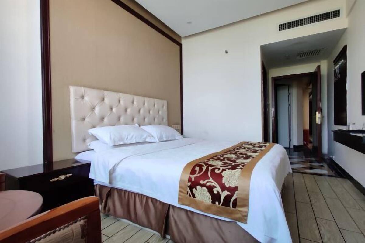 Une chambre d’hôtel avec un grand lit, une table de chevet en bois, un bureau et une chaise.