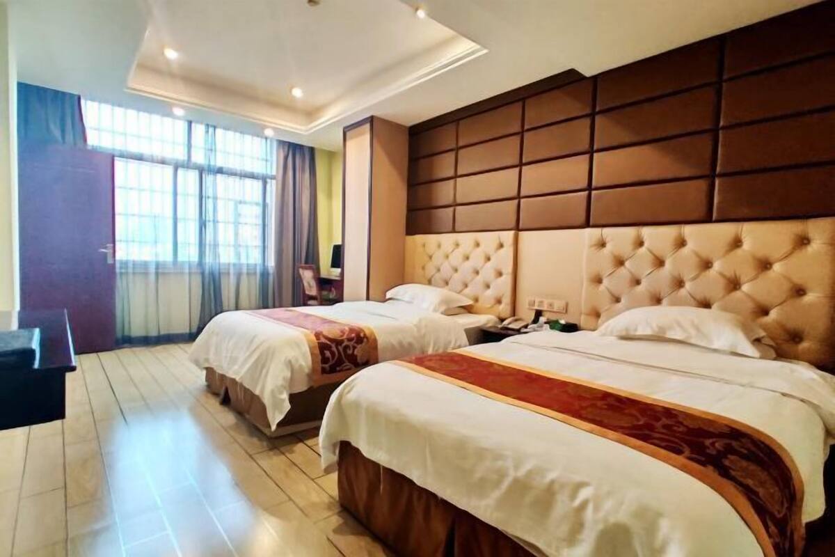 Une chambre d’hôtel avec deux lits, une grande fenêtre et une tête de lit moderne.