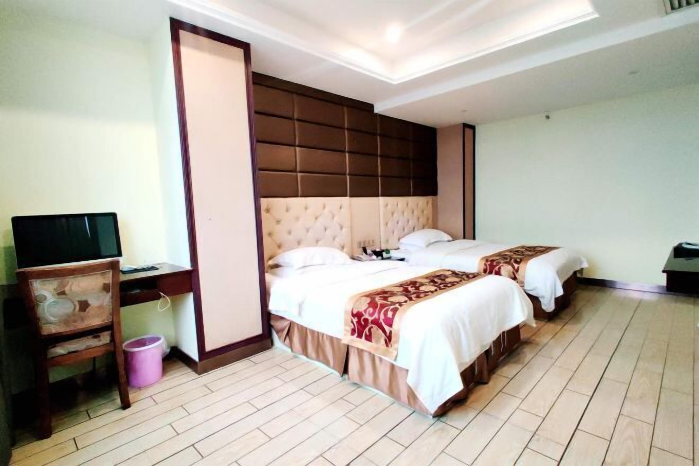 A hotel room with a large bed, a desk, and a television.