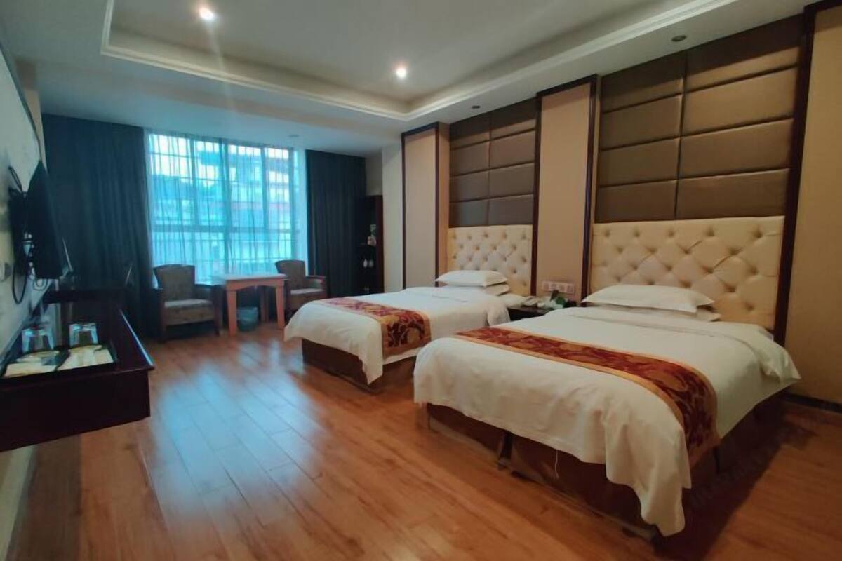 Une chambre d’hôtel avec deux lits, un bureau, une chaise et une télévision.