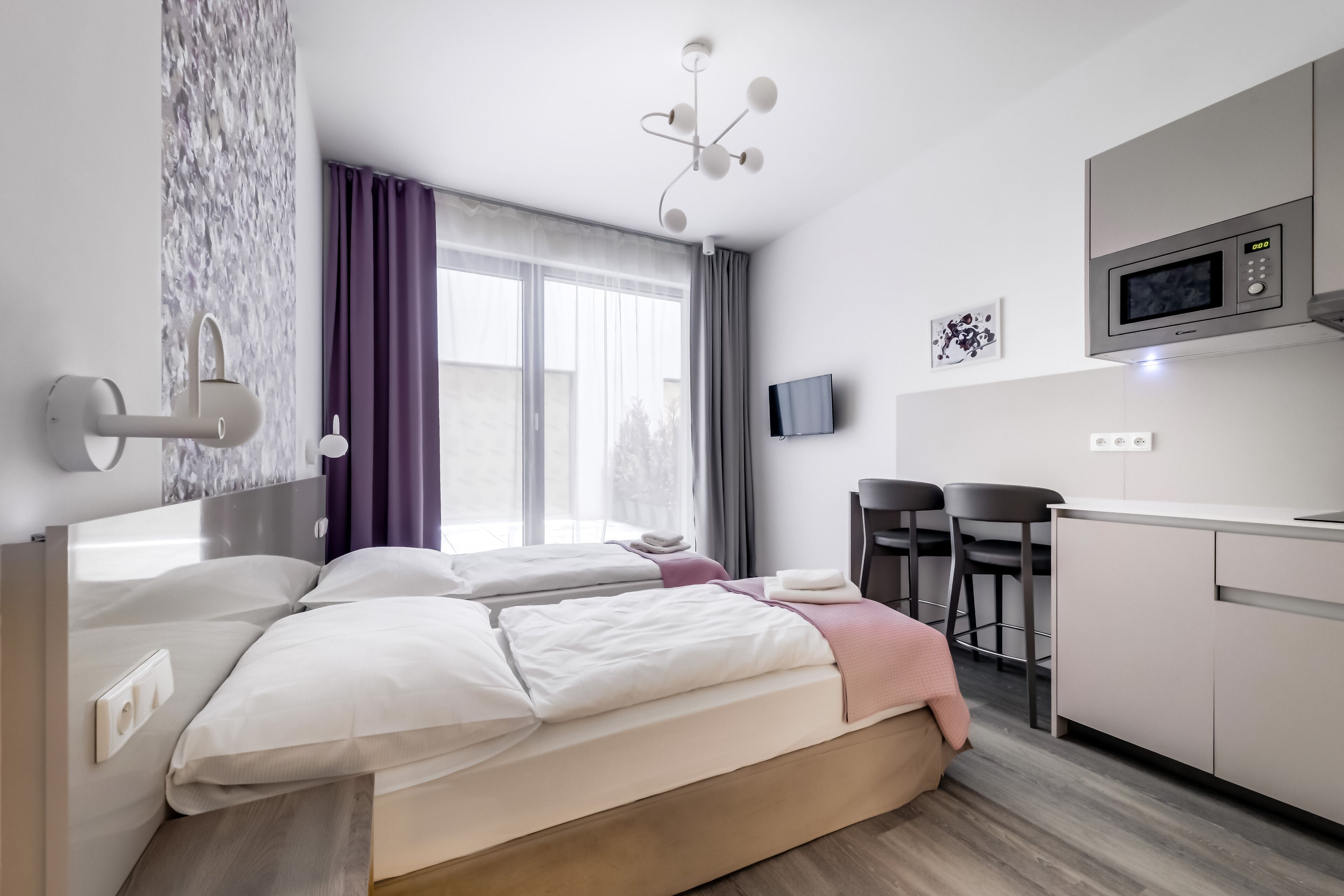Una habitación de hotel moderna con cama, escritorio, microondas y televisión.