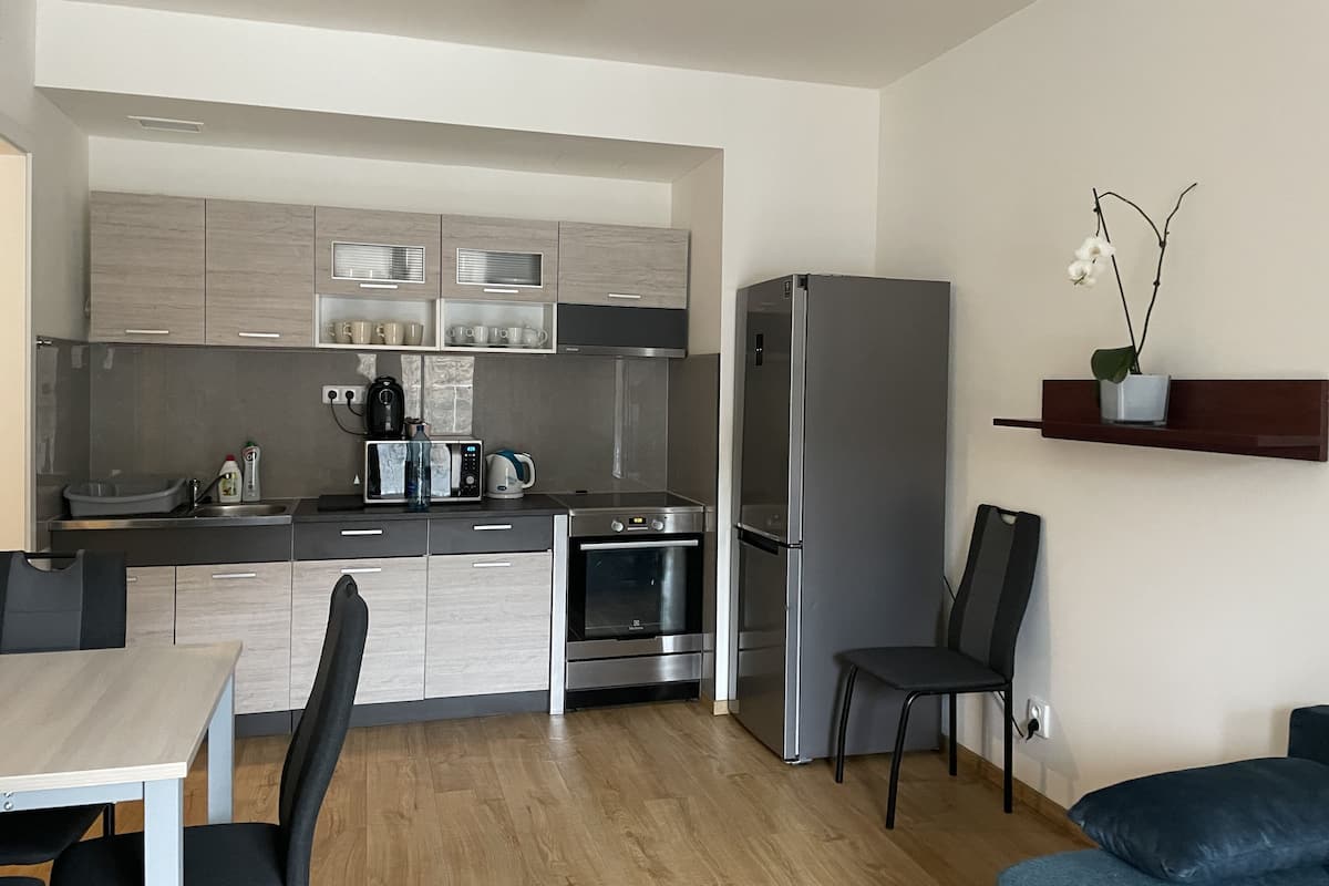 Eine moderne Küche mit eingebauten Geräten, ein Essbereich mit Tisch und Stühlen und eine kleine Sitzecke mit einer Couch.