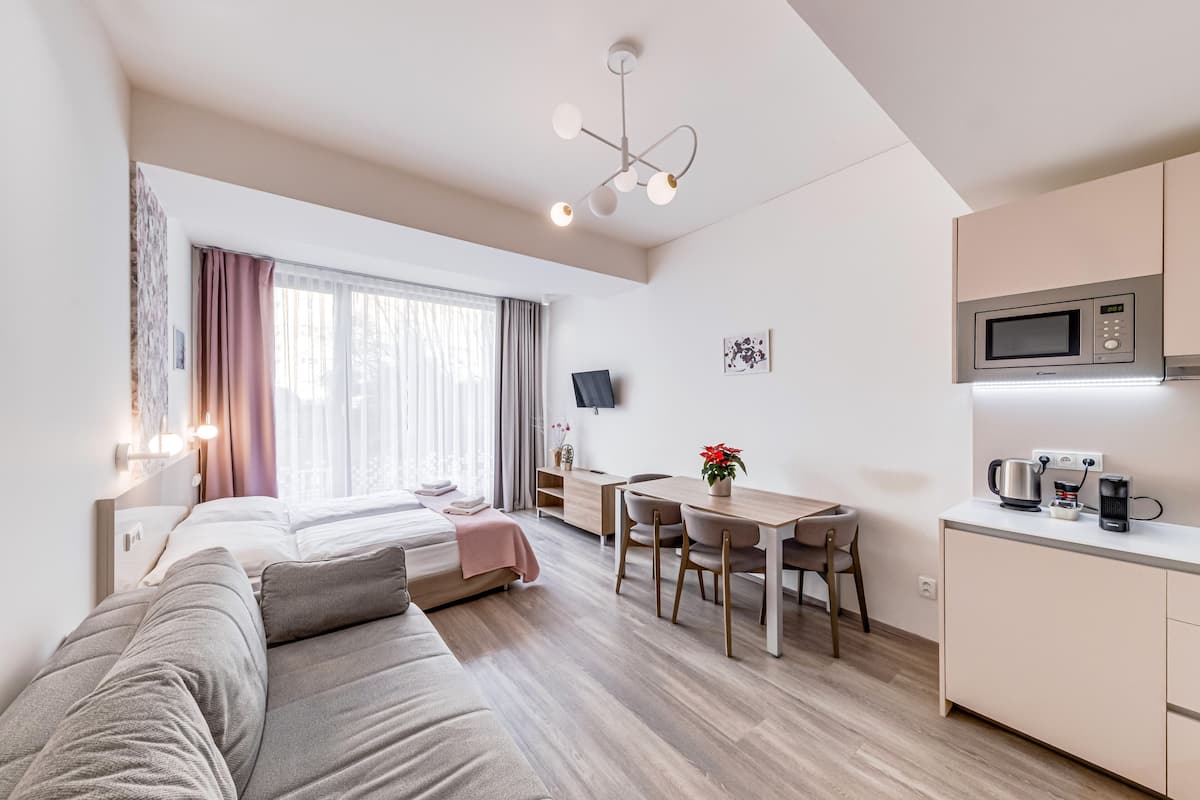 Ein modernes Hotelzimmer mit Bett, einer Couch, einem Essbereich, einer Küche und einem Fernseher.