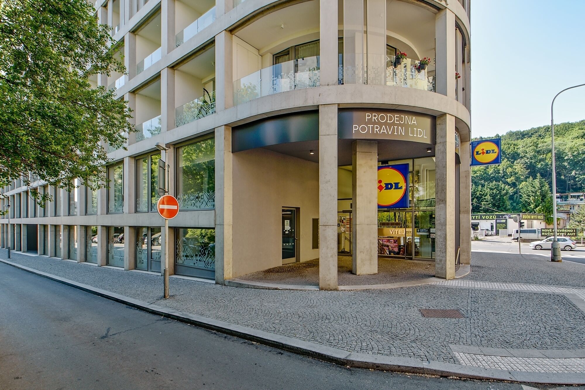 En modern byggnad med en Lidl-butik på bottenvåningen, kännetecknad av stora fönster och en väl synlig entré.