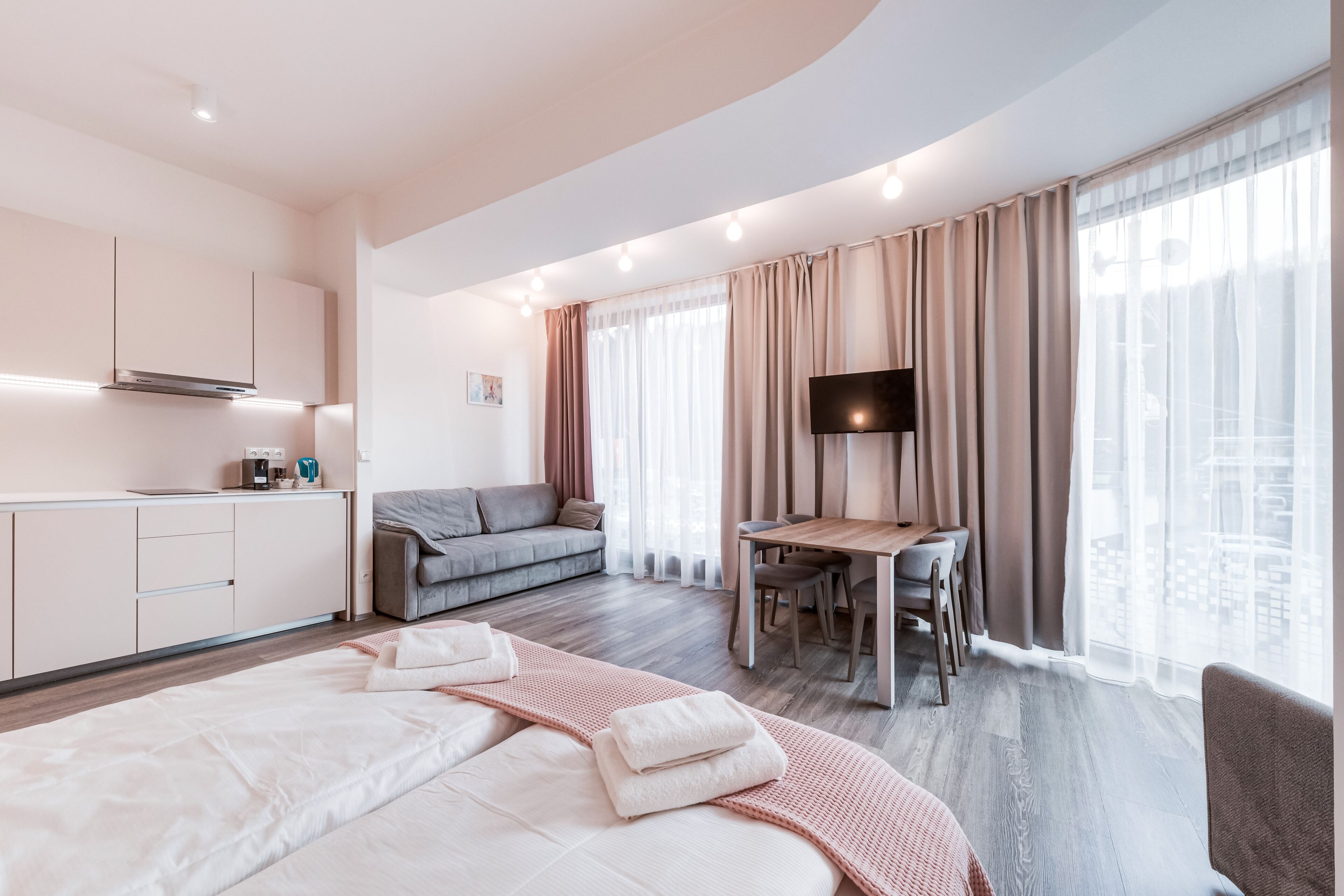 Una camera d'albergo moderna con un letto, una scrivania, un divano e una TV.