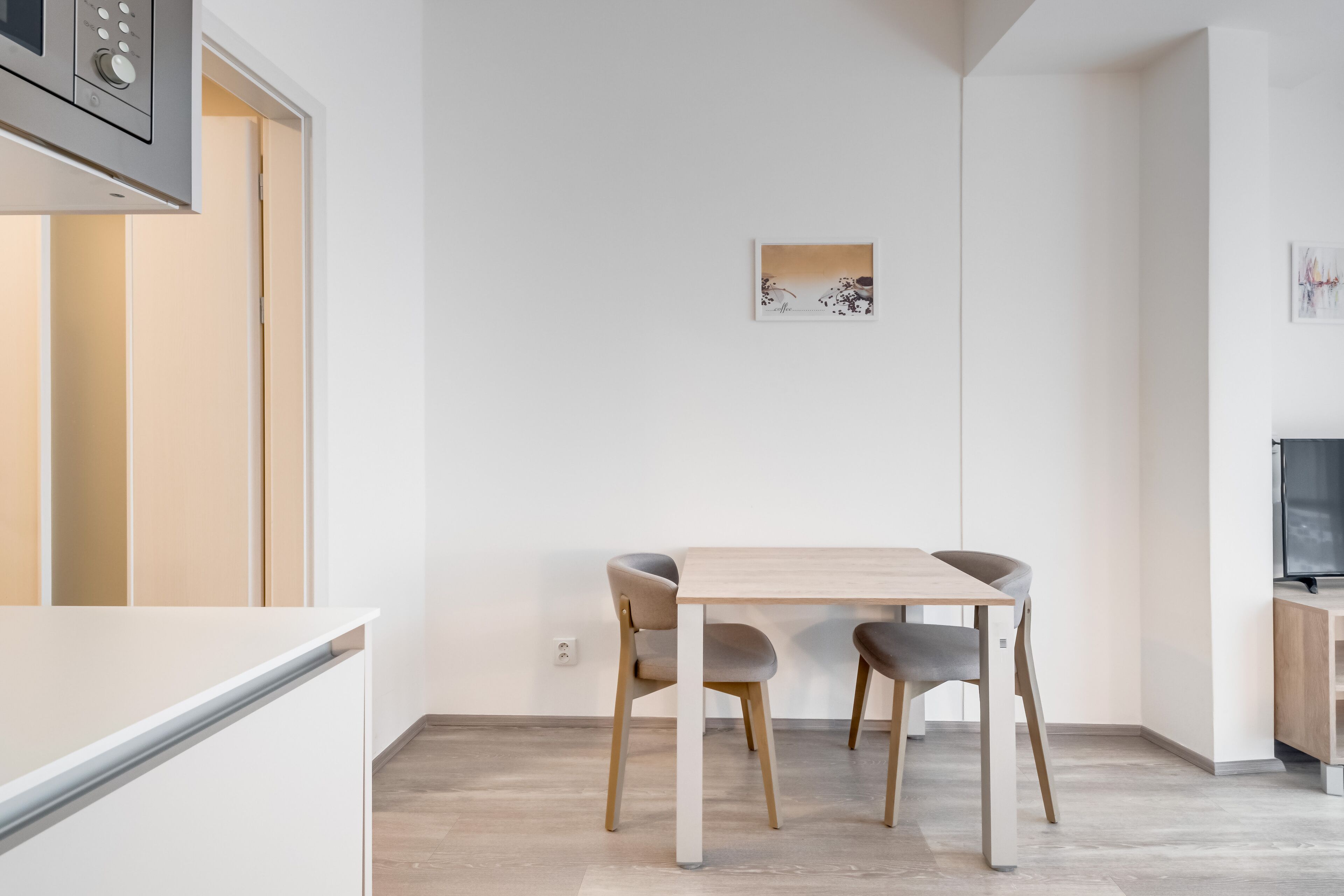 Une cuisine moderne avec une table et des chaises, un four à micro-ondes et un téléviseur.