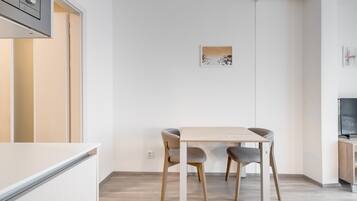 Une cuisine moderne avec une table et des chaises, un four à micro-ondes et un téléviseur.