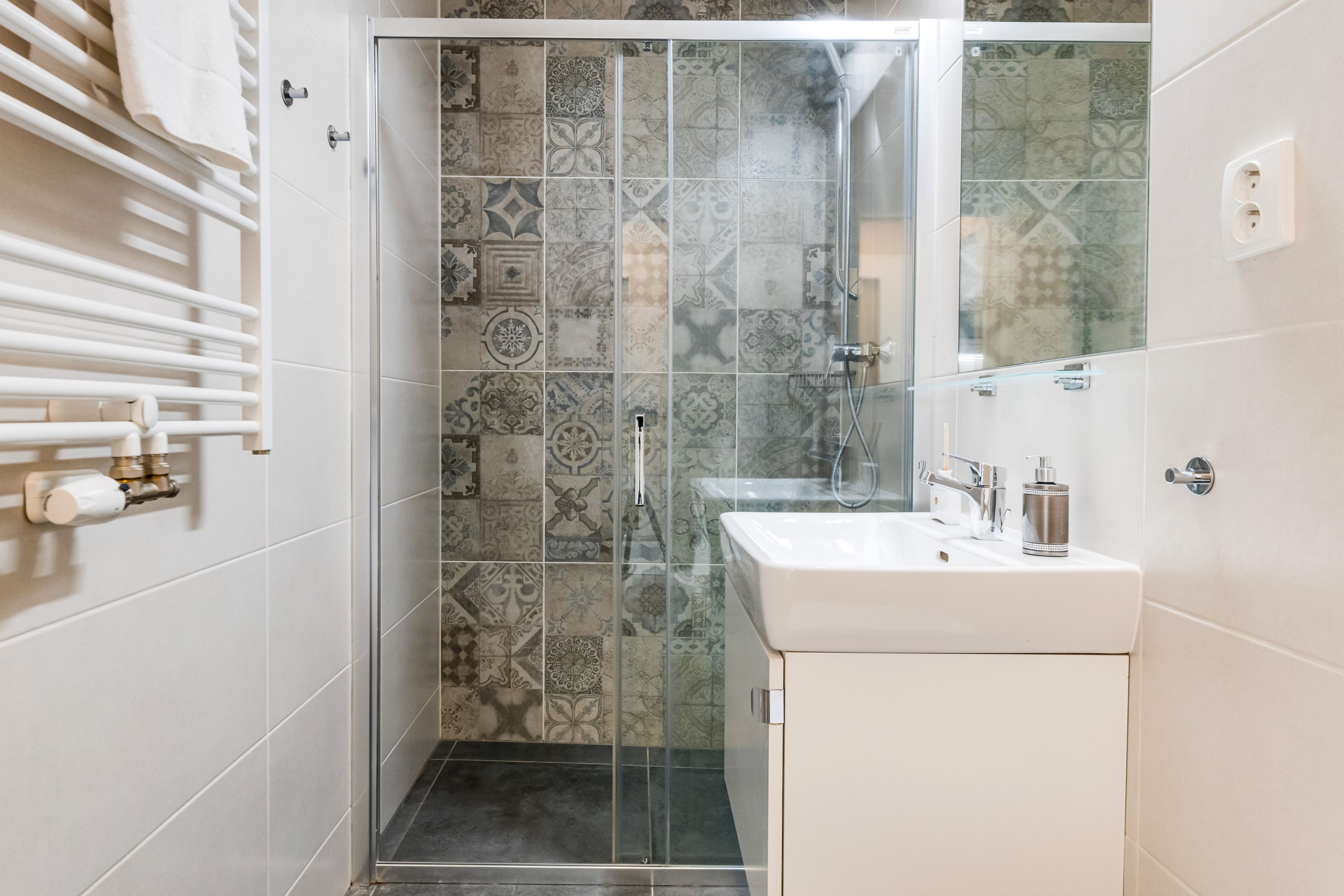 A bathroom with a shower, a sink, and a towel rack.