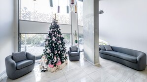 A modern living room with a large window, grey sofas, a Christmas tree, and a minimalist design. - KORA APARTMENTS (Prague)
