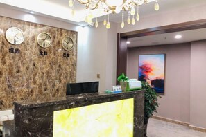 A reception desk with a marble wall, clocks, and a painting. - Changchun Meimei Business Hotel (Changchun)