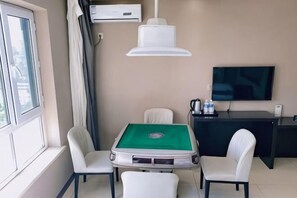 Quarto com mesa de bilhar, duas cadeiras, televisão e escrivaninha com computador.