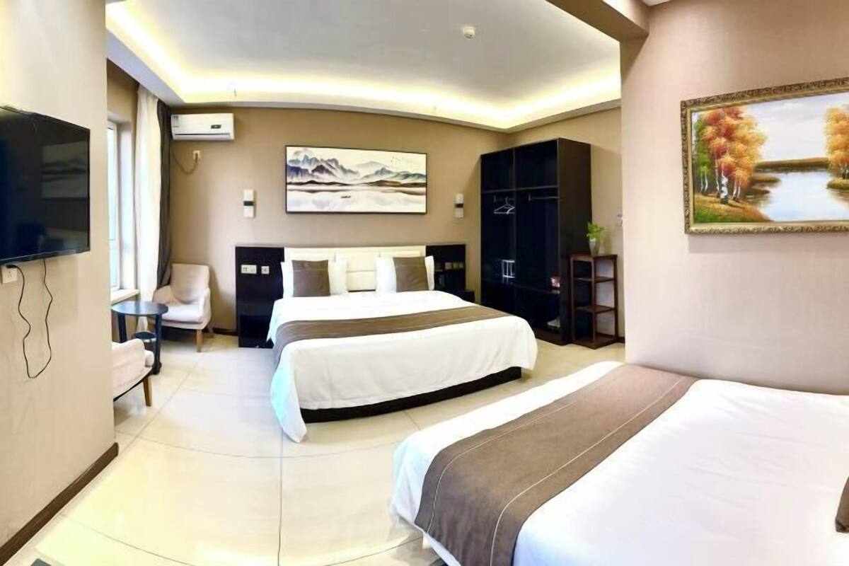 A hotel room with two beds, a flat-screen TV, a painting, and a wardrobe.
