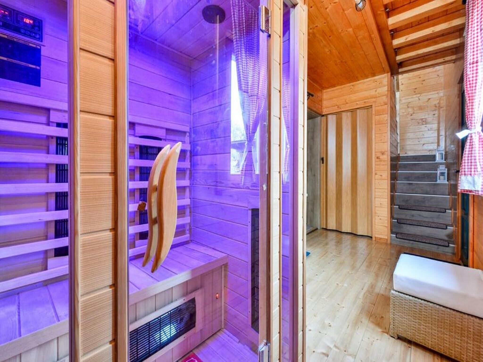 Uma sauna com paredes de madeira, um banco, um painel de controle e uma escada de madeira.