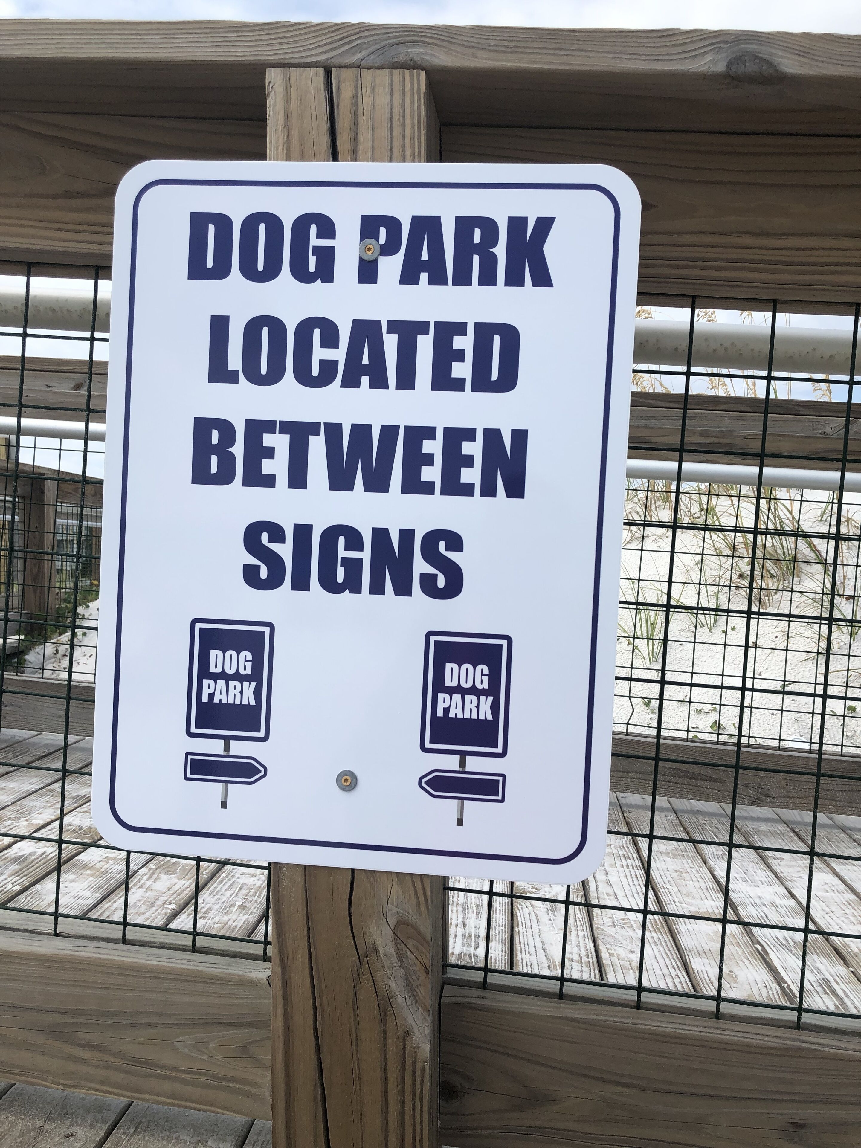 Skilt der viser en hundepark, placeret mellem andre skilte.
