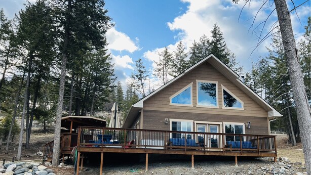 A two-story cabin with a deck, surrounded by trees. - Cleveland Cabin with Mountain Views & Lake Access (Rexford)