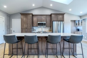 A modern kitchen with a central island, bar stools, and stainless steel appliances.