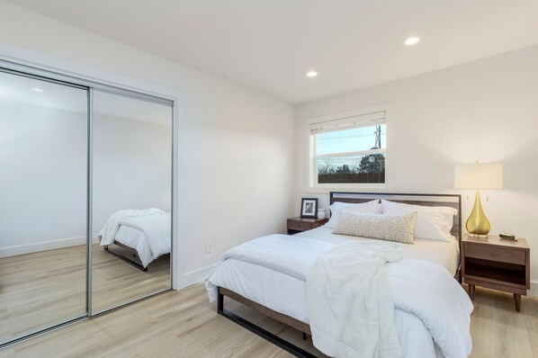 Una camera da letto con un letto, comodini, uno specchio e una finestra.