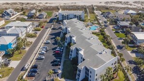 An aerial view of a coastal residential area with modern buildings, a parking lot, and a beach in the background. - Excellent Beach Location ~ Pool ~ Great Price! (Saint Augustine)