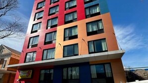 Ein mehrgeschossiges Gebäude mit modernem Design, das rote, blaue und beige Farbtöne kombiniert.