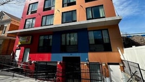 Ein mehrstöckiges Gebäude mit modernem Design, das rote, blaue und beigefarbene Elemente kombiniert.