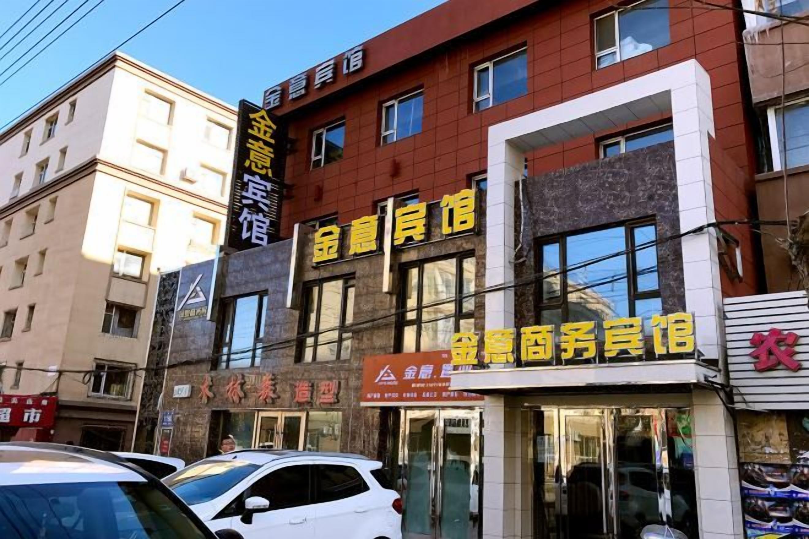 Un immeuble à plusieurs étages abritant divers commerces au rez-de-chaussée, notamment un hôtel et un centre de services.