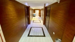 A hallway with wooden walls and a tiled floor, leading to a door at the end. - Jinyi Business Hotel (Changchun)