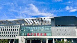 A modern building with a large glass facade and a sign that reads "房产交易市场" (Real Estate Trading Market). - Jinyi Business Hotel (Changchun)