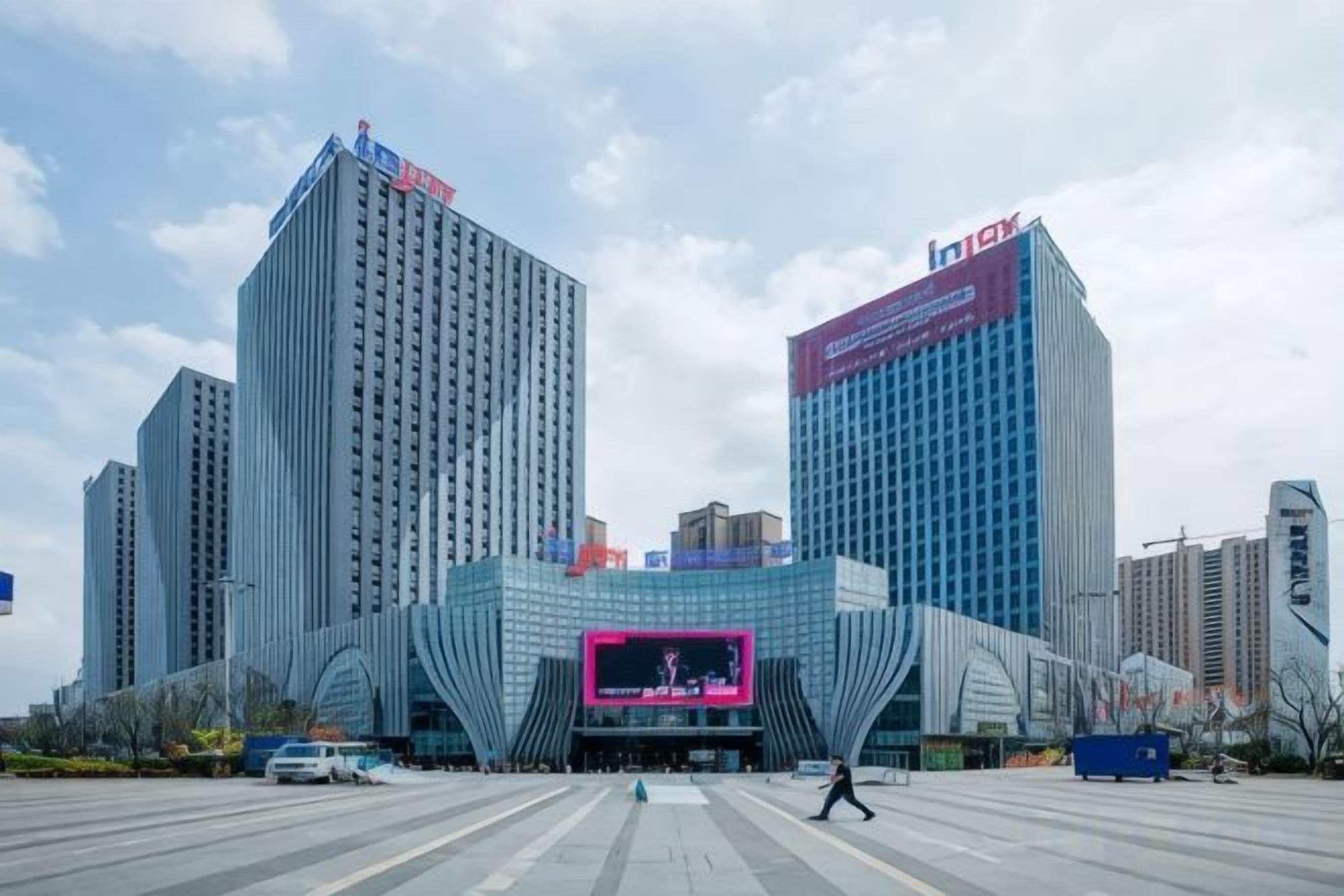 Un bâtiment moderne doté d’un grand écran numérique rose bien visible à l’entrée.