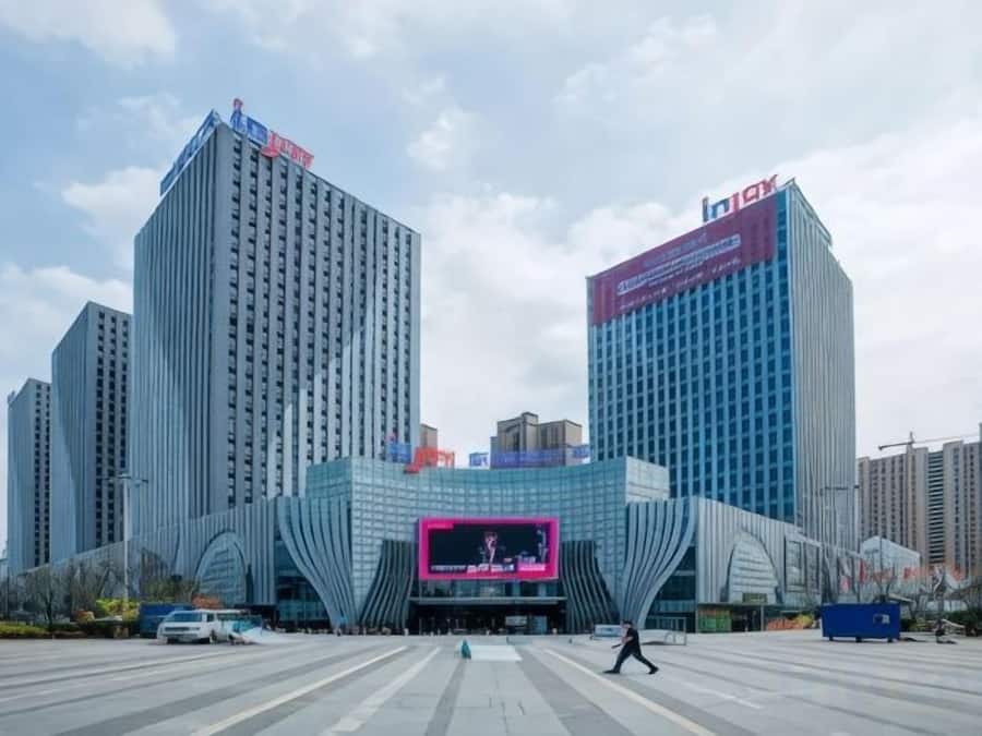 Un edificio moderno con un llamativo letrero digital rosa en la entrada.