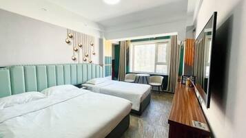 A hotel room with two beds, a small table, a TV, and a window with curtains.