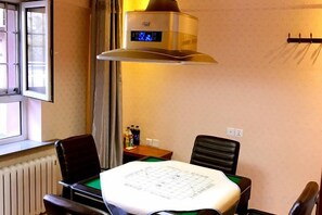 Une chambre d’hôtel avec une table à manger, des chaises, une cuisinière et une fenêtre.