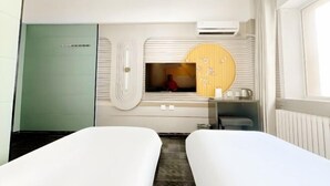 A hotel room with two beds, a green door, a vanity with a mirror, and a window with curtains. - Jinyi Business Hotel (Changchun)