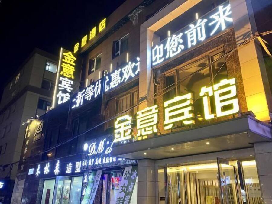 Een hotel met verlichte signage in een vreemde taal, dat meerdere verdiepingen en mogelijk verschillende diensten of kamers aangeeft.