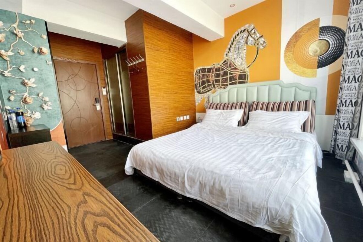 A modern bedroom with a large bed, a wooden table, and a decorative wall with a horse sculpture.
