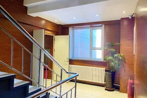 A staircase with metal railings leading to a landing, a large window with a view, and a potted plant. - Jinyi Business Hotel (Changchun)
