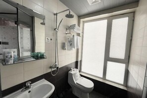 A bathroom with a bathtub, toilet, and a window. - Jinyi Business Hotel (Changchun)