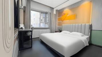 Una habitación de hotel moderna con una cama grande, un escritorio y una ventana.