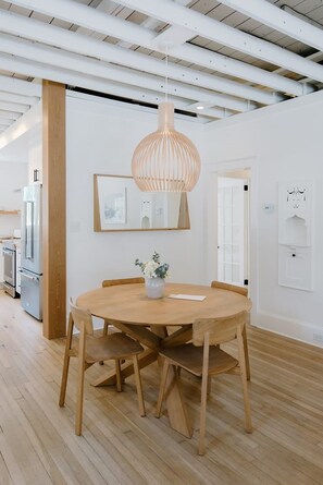 Eine moderne Küche mit einem runden Holztisch, Holzstühlen und einer hängenden Leuchte.