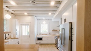 Una cocina moderna con armarios blancos, un refrigerador de acero inoxidable y piso de madera.