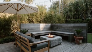 Terraza de madera con banco integrado y un brasero.