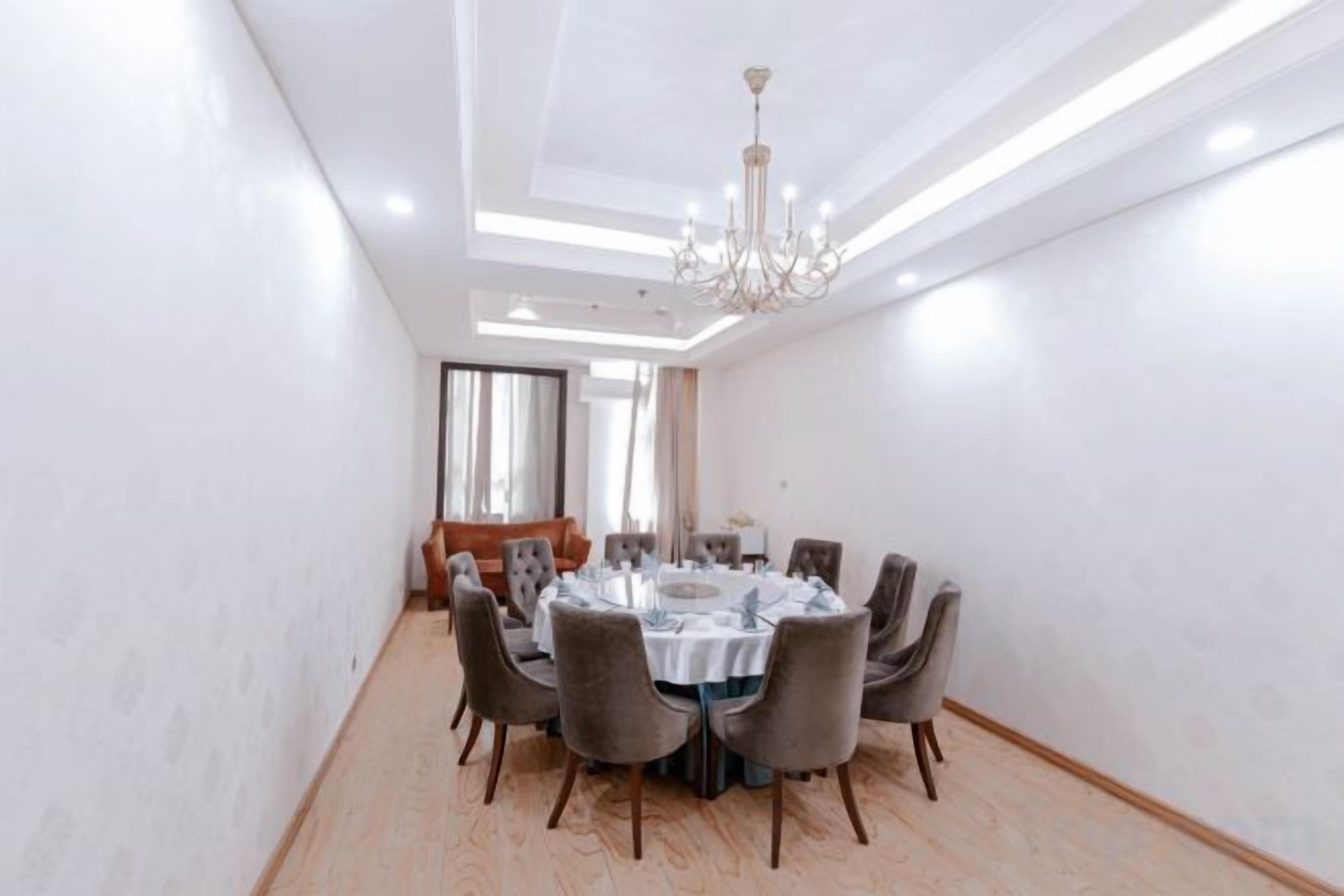A conference room with a round table, chairs, and a chandelier.